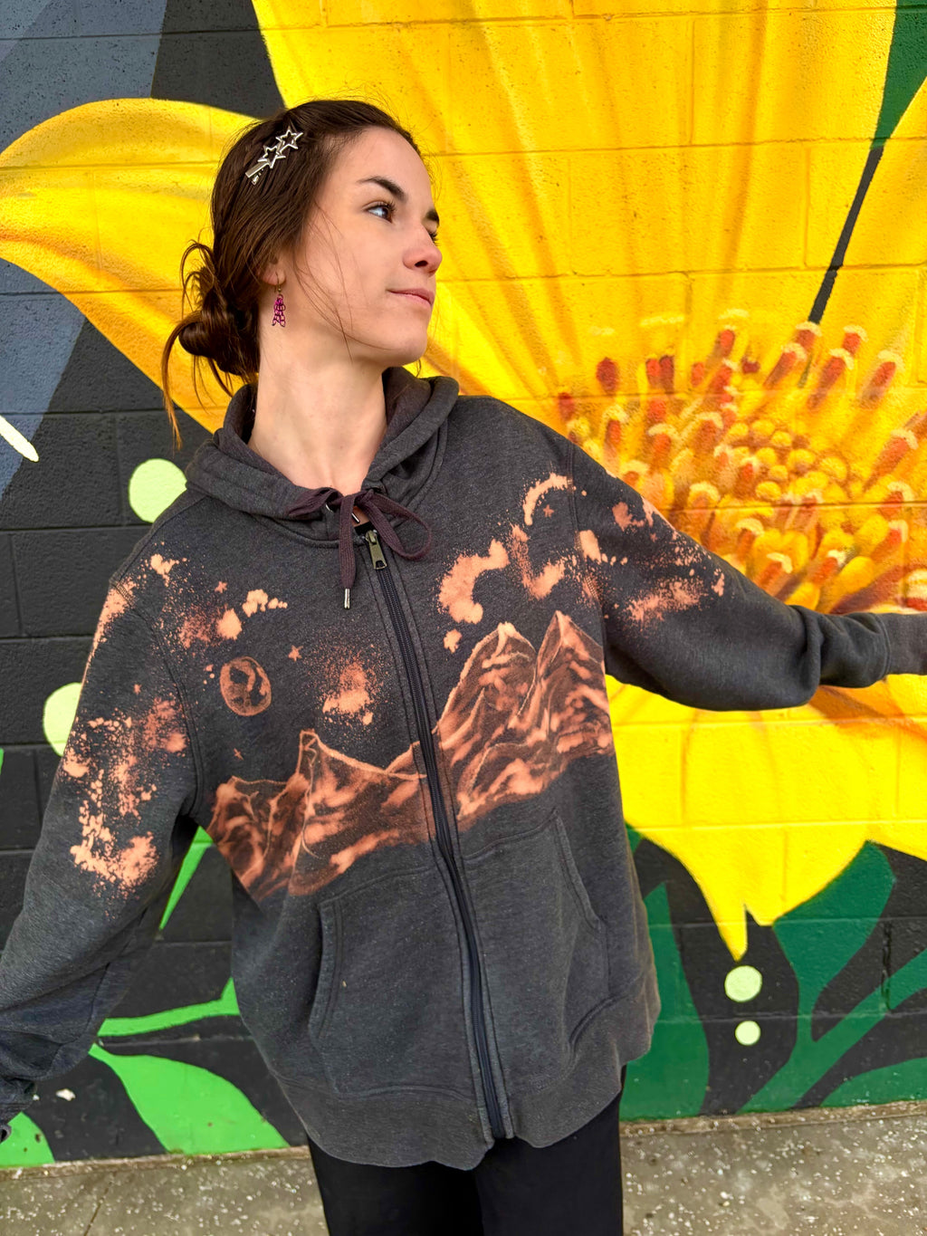 hand-painted bleach art of a mountain on a zip up hoodie with stars and a moon 