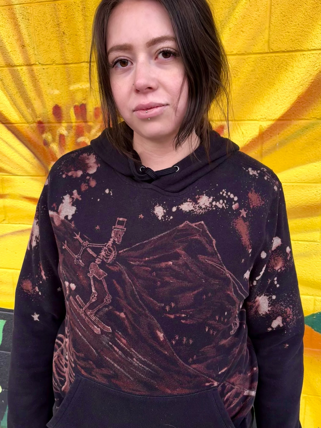 black hoodie hand-painted bleach art skeleton ski going down slope with people going up ski lift