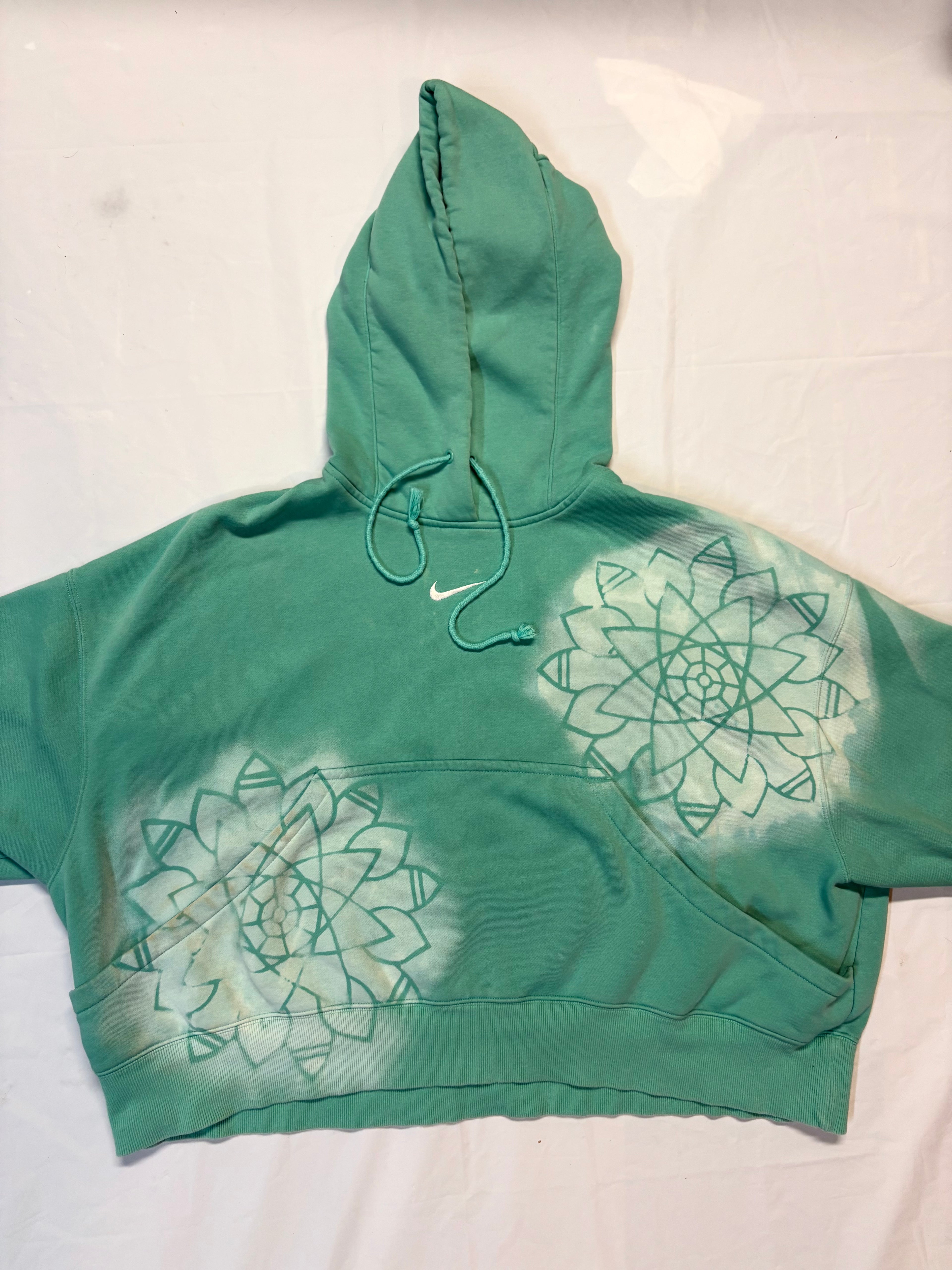 Green hoodie with mandala design on a white background