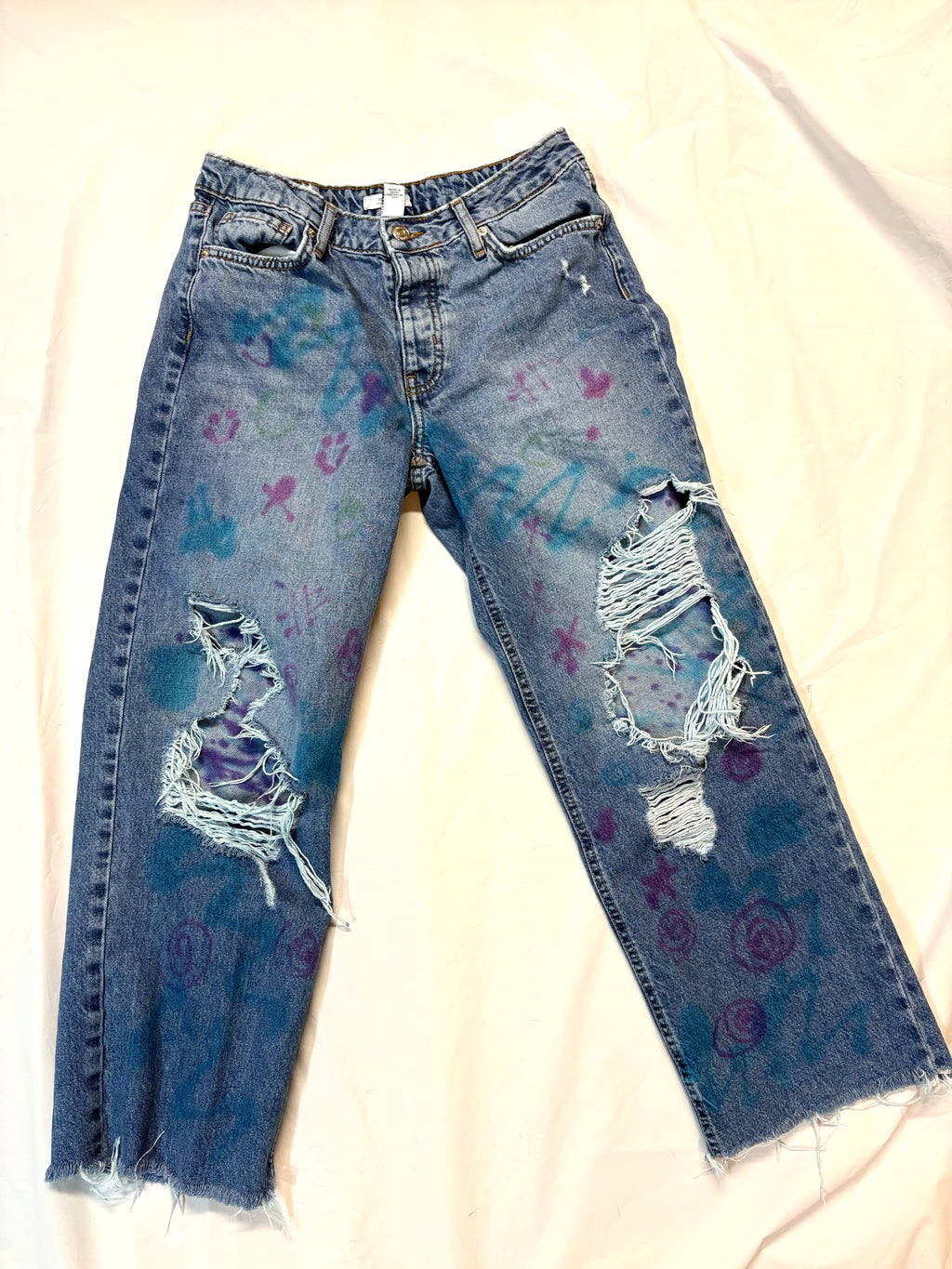 Blue jeans with artistic designs on a white background